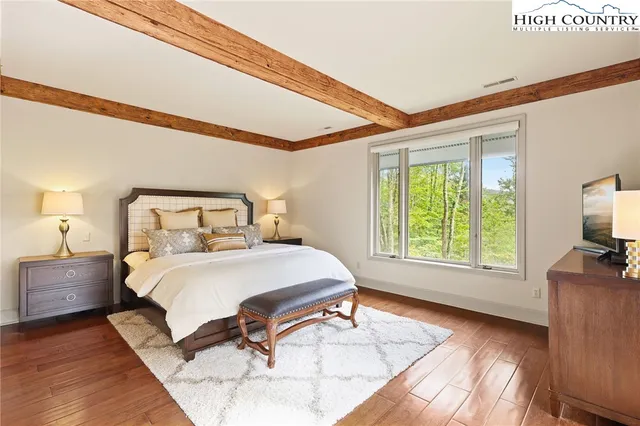 a bedroom with a bed and a flat tv screen on dresser