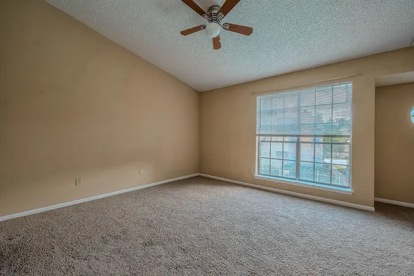 an empty room with windows and ceiling fan