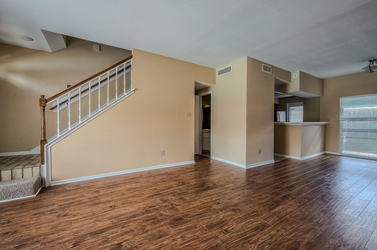 11201 Lynbrook Drive, Unit 3202 Houston, TX 77042 - Photo 4 of 22 a view of an empty room with wooden floor and a kitchen