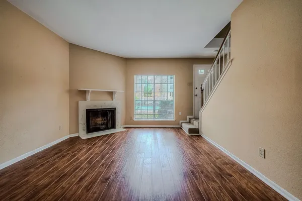 an empty room with wooden floor fireplace and windows