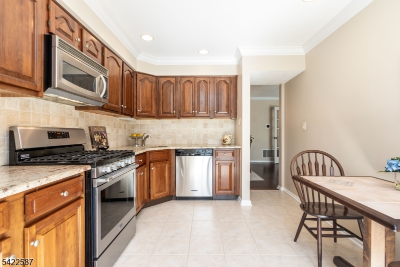 504 Reading Circle Bridgewater, NJ 08807 - Photo 15 of 35 a kitchen with stainless steel appliances granite countertop a stove top oven a sink dishwasher and a refrigerator with wooden cabinets