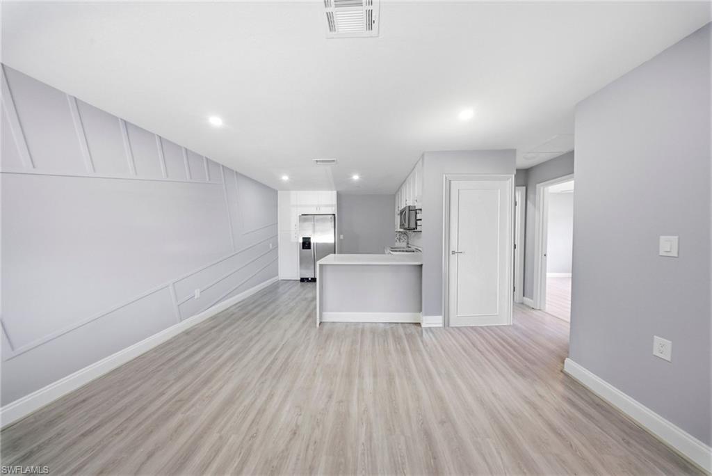 4375 Golden Gate Parkway Naples, FL 34116 - Photo 11 of 34 Unfurnished living room with a decorative wall, light wood-type flooring, and recessed lighting