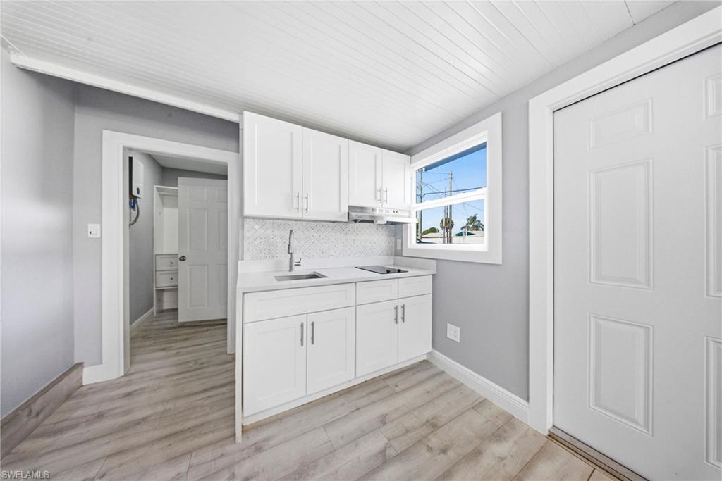 4375 Golden Gate Parkway Naples, FL 34116 - Photo 24 of 34 Kitchen with white cabinets, light wood-style floors, backsplash, wood ceiling, and black electric stovetop