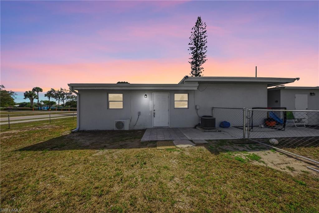4375 Golden Gate Parkway Naples, FL 34116 - Photo 32 of 34 Back of house at dusk featuring stucco siding, a patio, and a gate