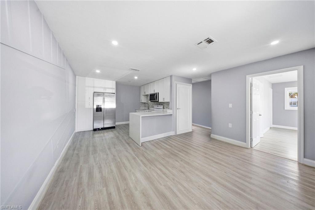 4375 Golden Gate Parkway Naples, FL 34116 - Photo 8 of 34 Kitchen with stainless steel appliances, light countertops, open floor plan, white cabinets, and light wood-style floors