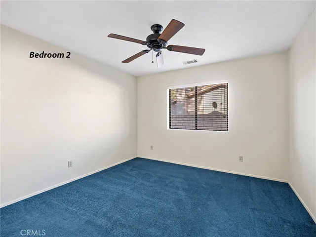 an empty room with window and ceiling fan