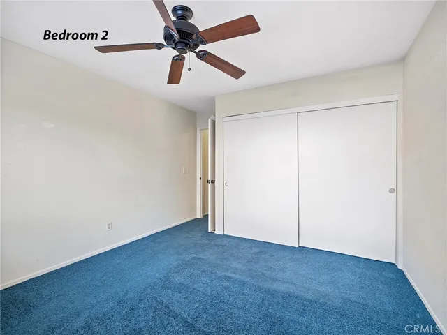 an empty room with a ceiling fan and carpet