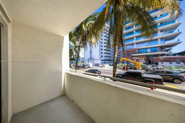 a view of a street with a building and palm trees