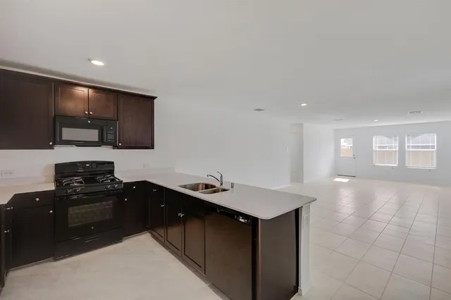 a kitchen with a sink and a stove top oven with wooden floor