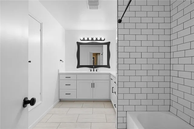a bathroom with a bathtub sink vanity and mirror