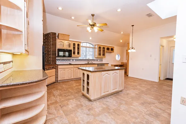 a view of kitchen with kitchen island granite countertop a stove top oven a sink and dishwasher