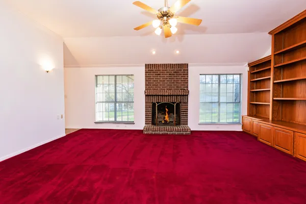 an empty room with windows and a fireplace