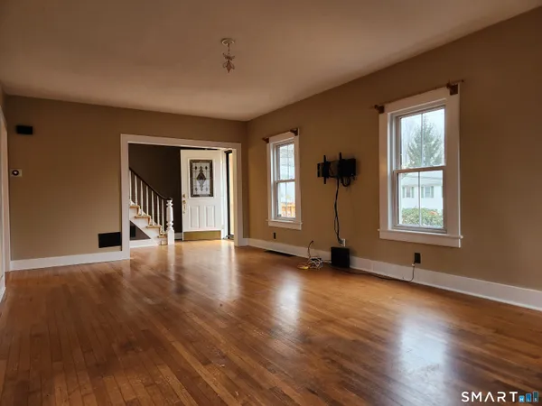a view of an empty room with wooden floor and a window