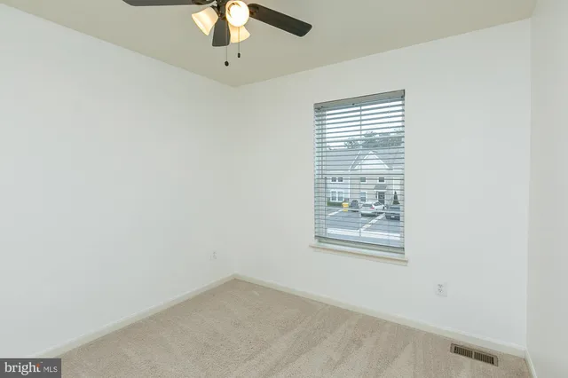 a view of empty room with a ceiling fan and window