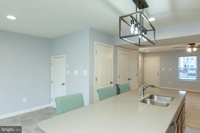 a kitchen with stainless steel appliances a sink a stove a refrigerator cabinets and a dining table