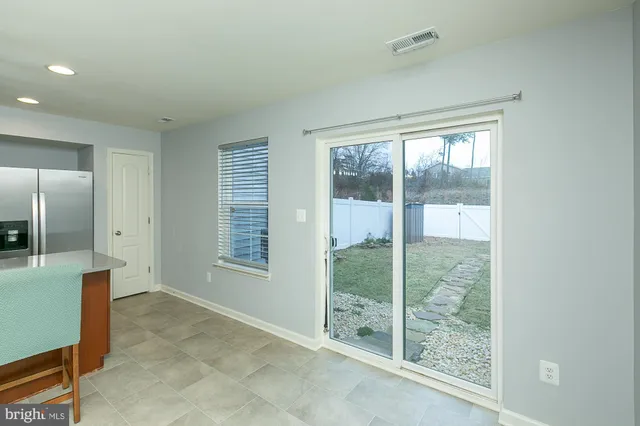 an empty room with chandelier fan and windows