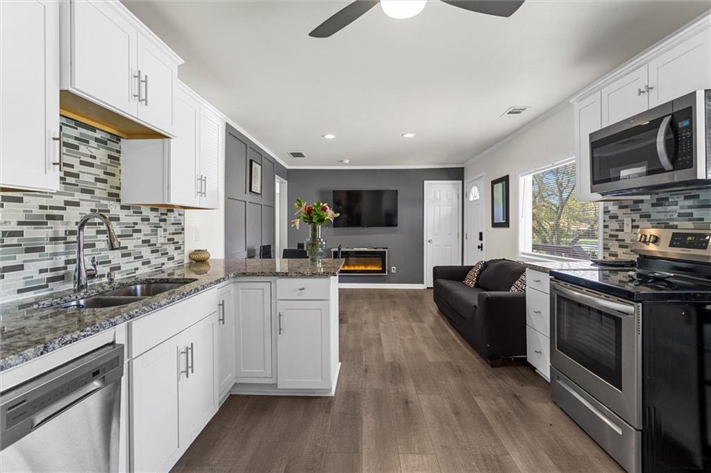1111 Valley View Road Southeast Atlanta, GA 30315 - Photo 4 of 31 a kitchen with stainless steel appliances granite countertop a stove top oven a sink dishwasher a refrigerator and white cabinets with wooden floor