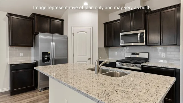 a kitchen with granite countertop a refrigerator and a stove top oven