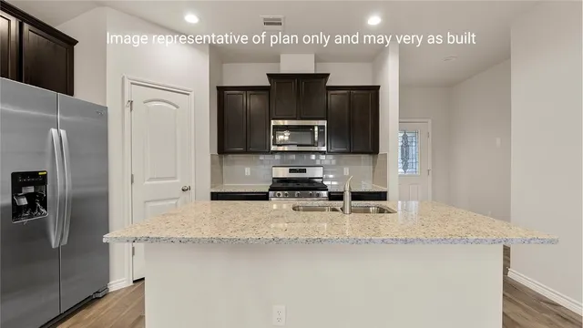 a kitchen with stainless steel appliances granite countertop a refrigerator and a stove top oven