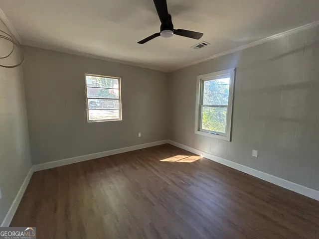 a view of an empty room with wooden floor and a window