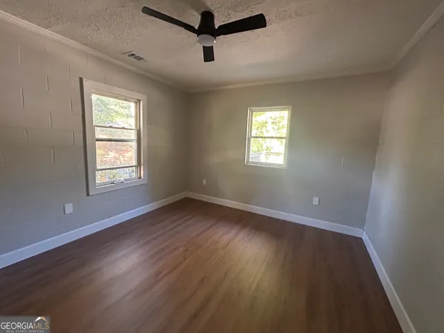 a view of an empty room with wooden floor and window