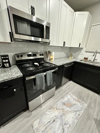 a kitchen with stainless steel appliances kitchen island granite countertop a stove a sink and a microwave