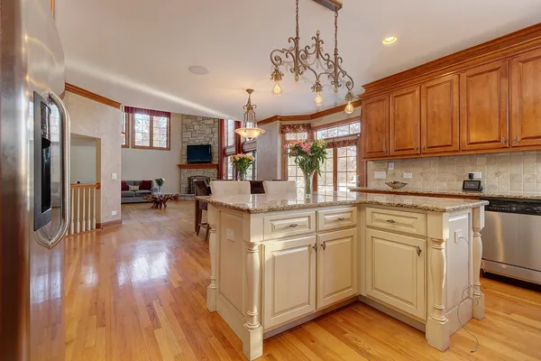 a kitchen with stainless steel appliances granite countertop a refrigerator a sink dishwasher a stove and white cabinets with wooden floor