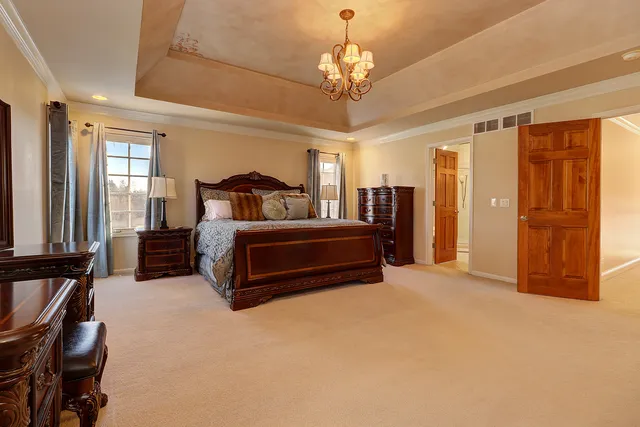 a spacious bedroom with a bed and a chandelier
