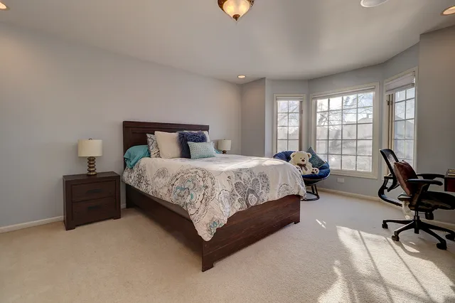 a bedroom with a bed a chair and a piano next to a large window