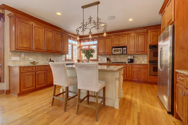 a kitchen with stainless steel appliances a dining table chairs sink and cabinets