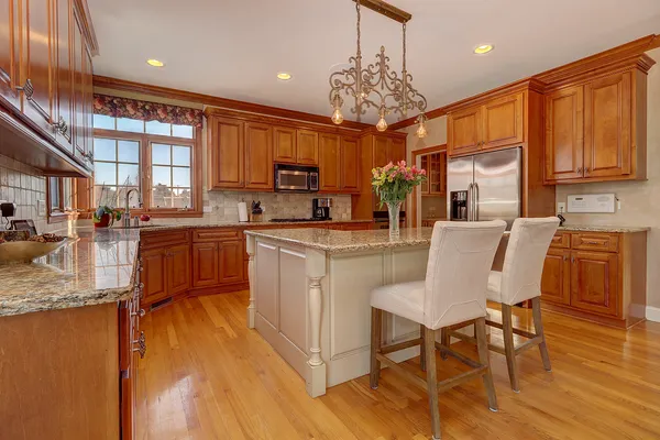 a kitchen with stainless steel appliances granite countertop a stove top oven a sink dishwasher a dining table and chairs with wooden floor