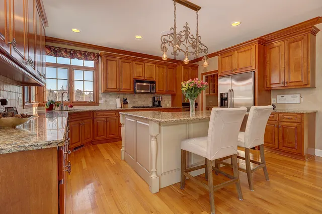 a kitchen with stainless steel appliances granite countertop a stove top oven a sink dishwasher a dining table and chairs with wooden floor