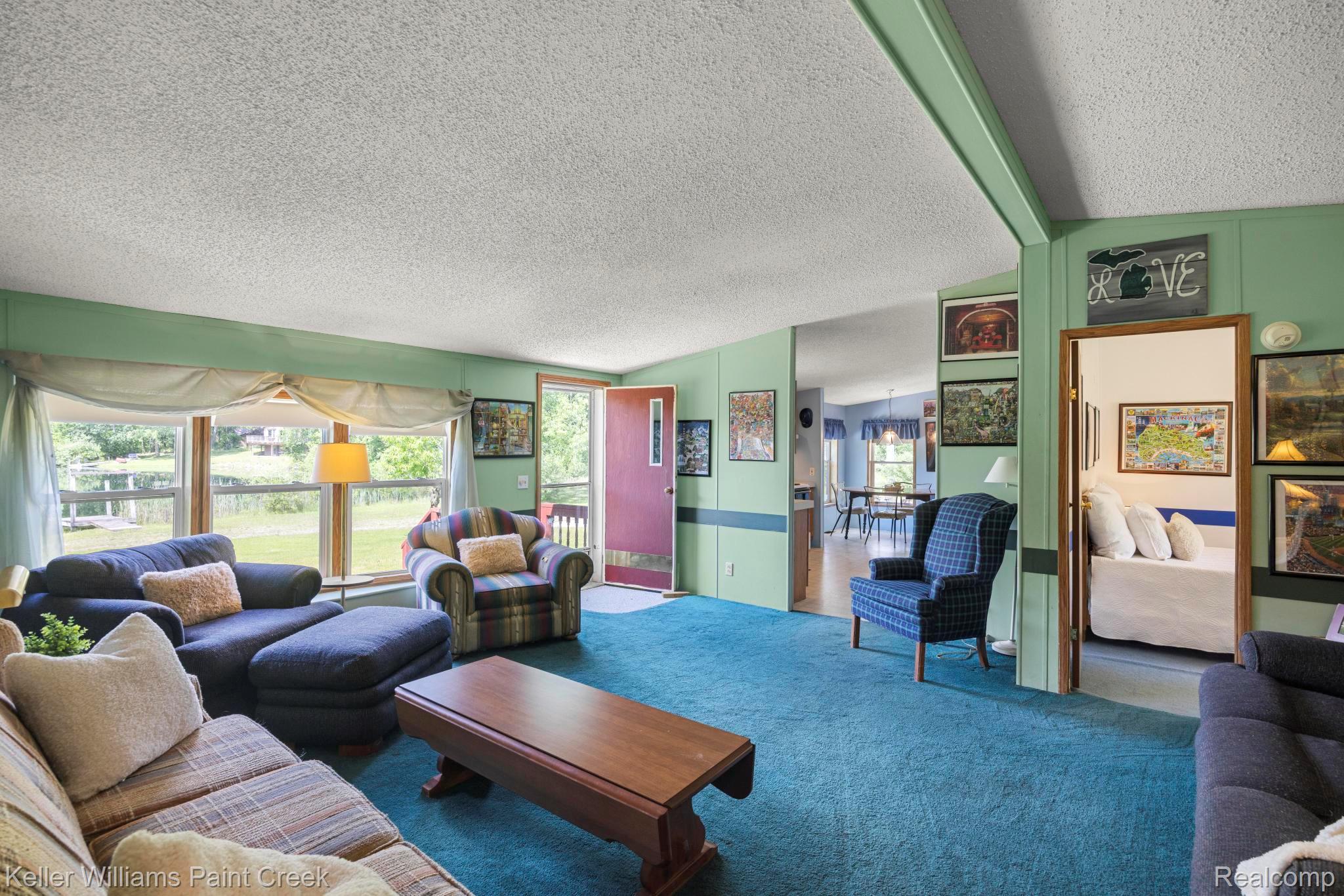 2457 West Harrington Road Croswell, MI 48422 - Photo 11 of 42 Spacious living area featuring a large picture window, teal carpeting, and light green wall paneling