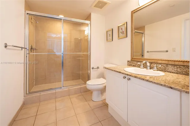 a bathroom with a granite countertop sink toilet a mirror and shower