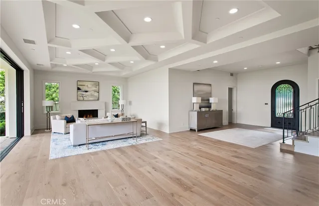 a large room with lots of white furniture wooden floor and a large window