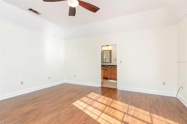 an empty room with wooden floor closet and windows
