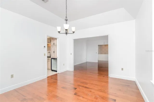 a view of empty room with wooden floor and chandelier