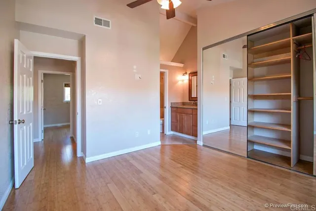 a view of an empty room with wooden floor closet and a window
