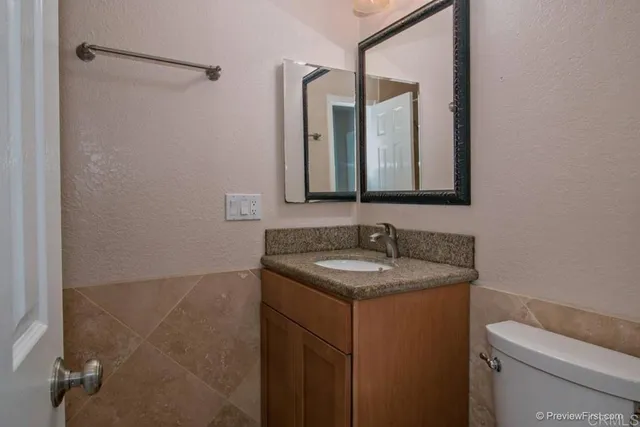 a bathroom with a granite countertop sink a toilet and a mirror