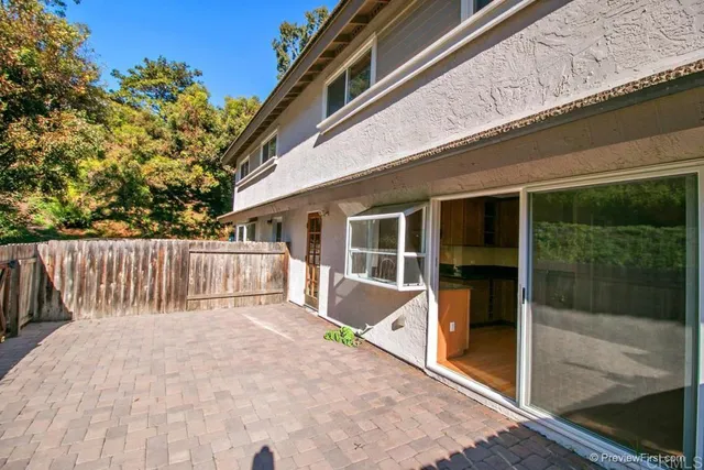 a view of backyard with large trees and wooden fence