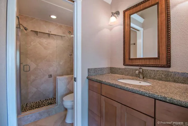 a bathroom with a granite countertop sink toilet and shower
