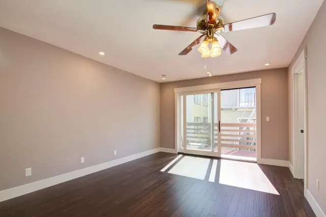 a view of a hallway with wooden floor and a ceiling fan