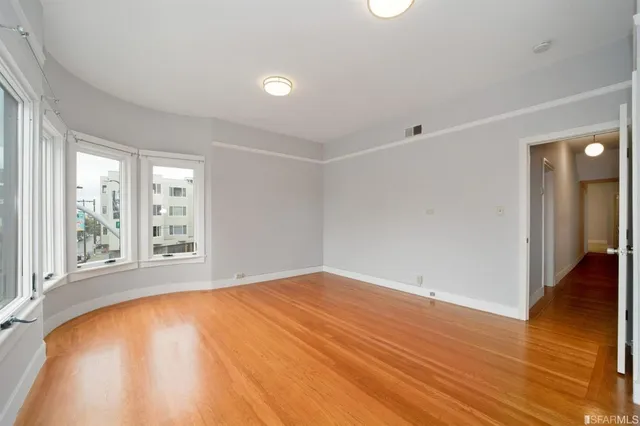 a view of a hallway with wooden floor and a bathroom