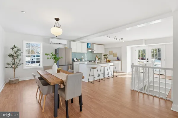 a kitchen with stainless steel appliances granite countertop a refrigerator a sink dishwasher a stove a dining table and chairs with wooden floor