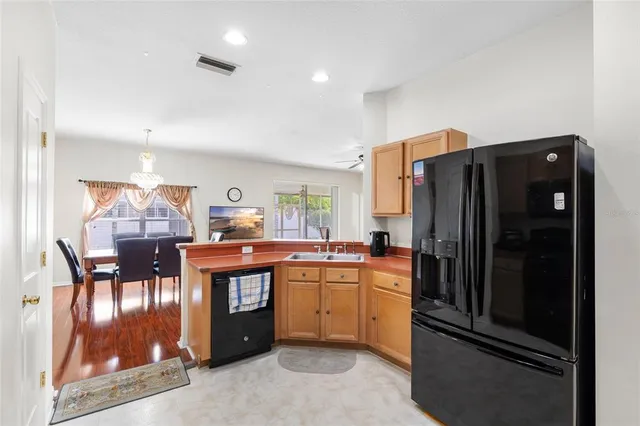 a kitchen with stainless steel appliances granite countertop a refrigerator a sink a stove and chairs