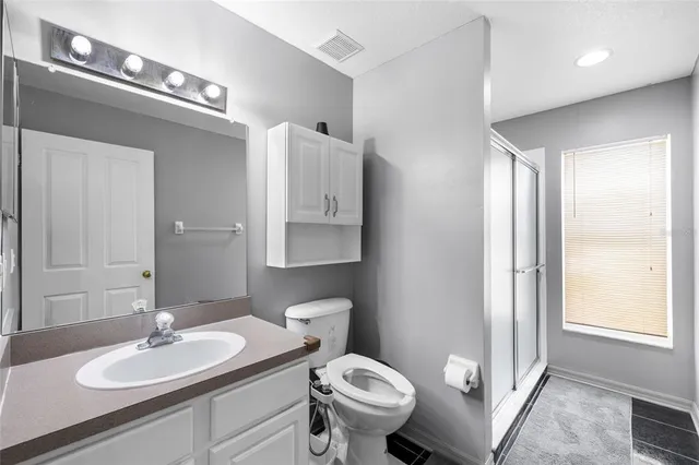 a bathroom with a granite countertop sink mirror vanity and toilet