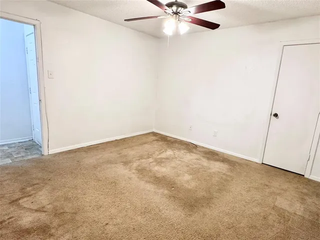 an empty room with a fan & a window