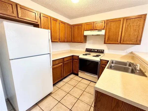 a kitchen with stainless steel appliances granite countertop a refrigerator a stove and a sink