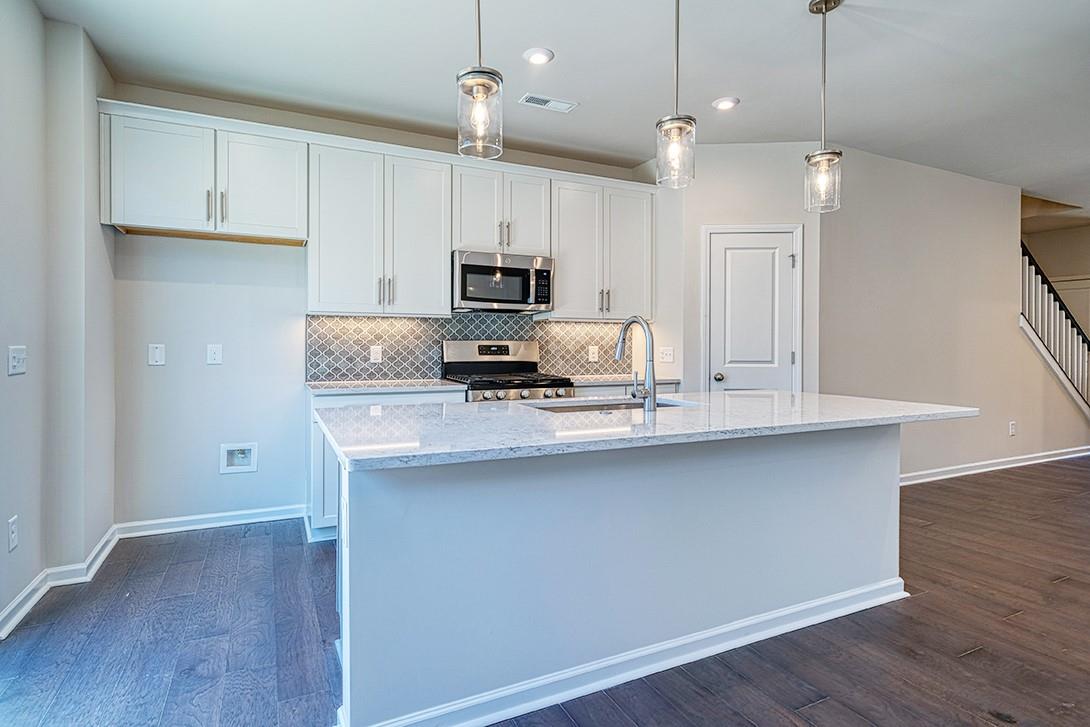 a kitchen with kitchen island a counter space a sink appliances and cabinets