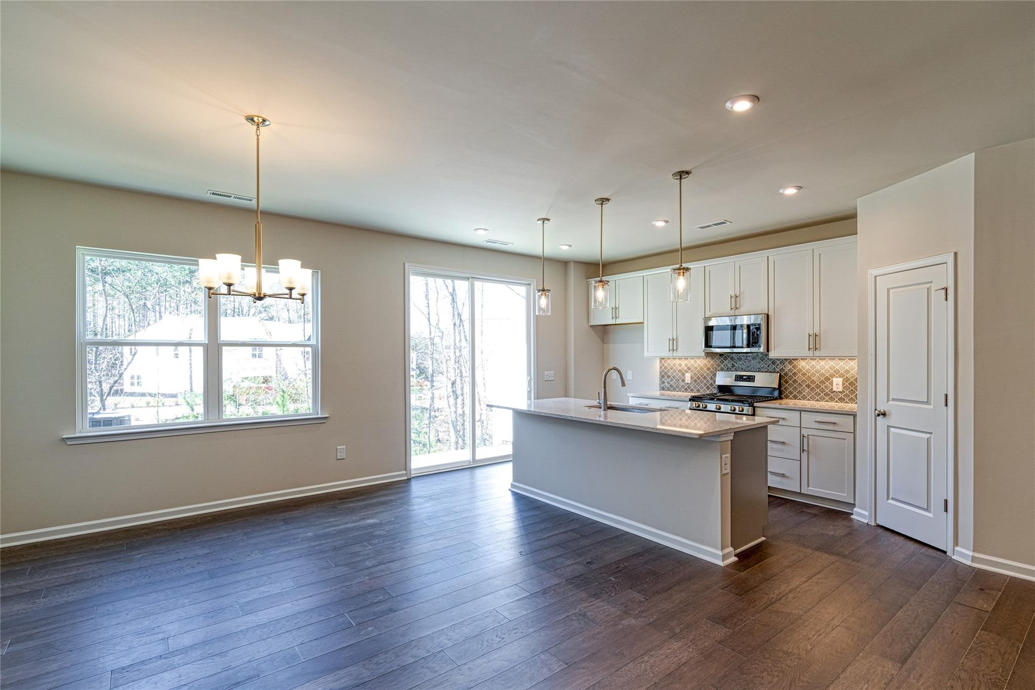 513 Madison Falls Court Fort Mill, SC 29708 - Photo 3 of 37 a kitchen with kitchen island granite countertop a stove a sink a refrigerator and white cabinets with wooden floor